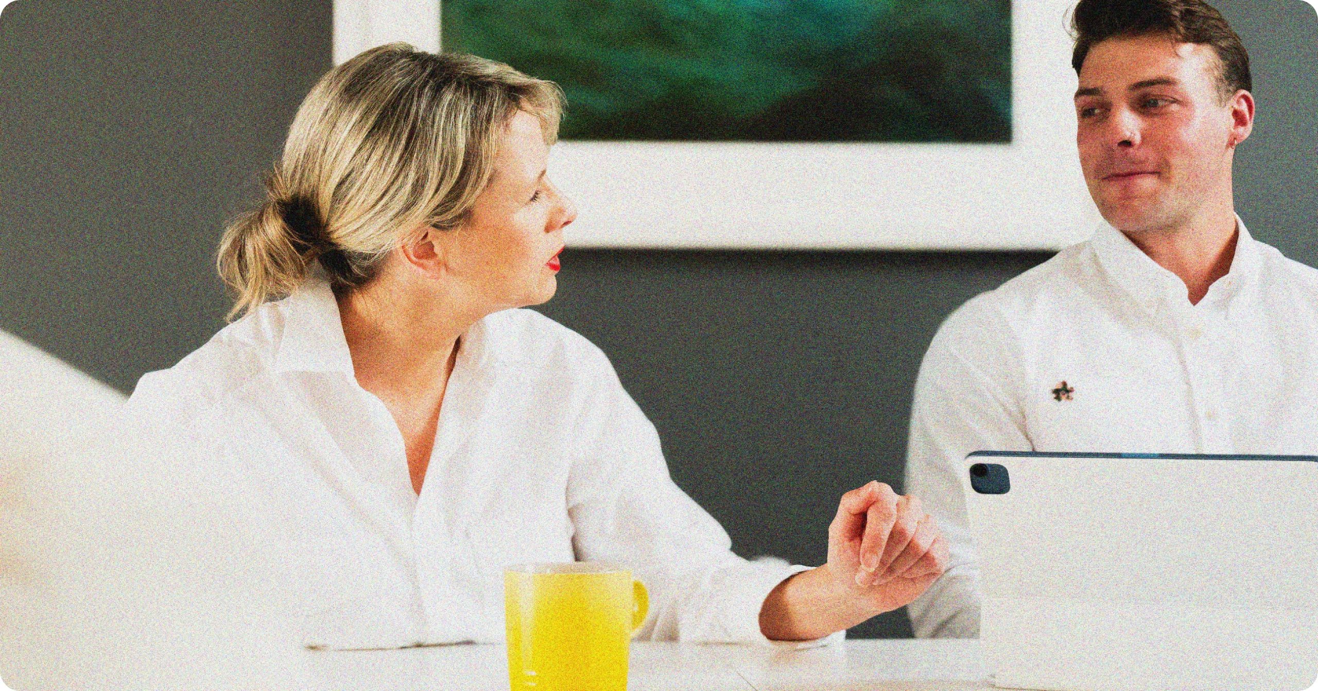 A woman looks at a man as she speaks to him during a coaching session on leadership and company culture.