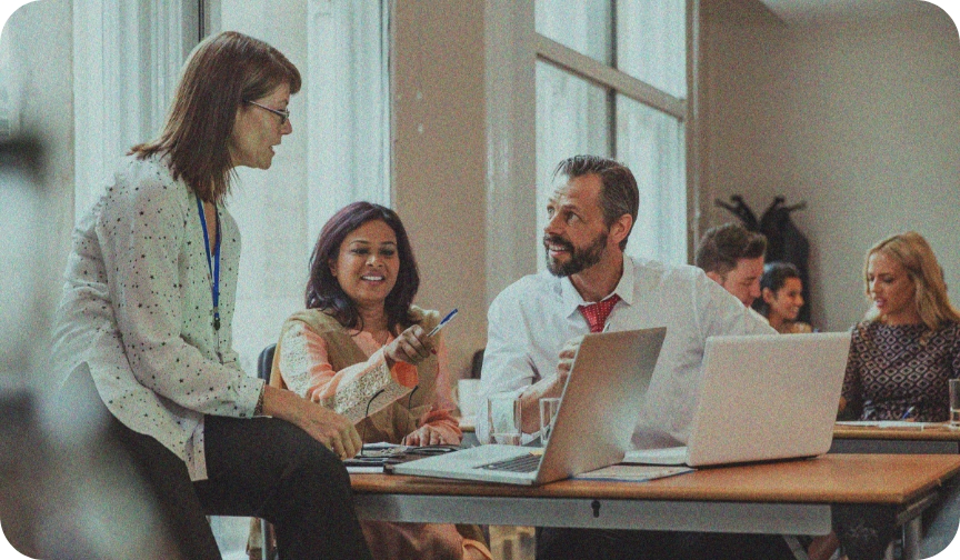 Two women and a man look at a laptop in a work setting, illustrating the collaborative benefits of a great company culture.