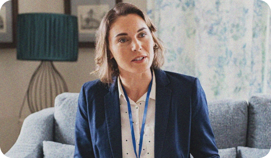 A woman in a suit sits with a reflective expression as she speaks to a strengths coach, who is out of shot.